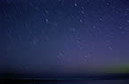 Time exposure of stars above a Lake Michigan beach.